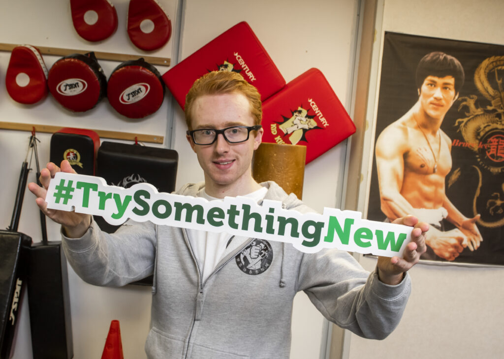 Ryan Cuzen holding a #TrySomethignNew sign