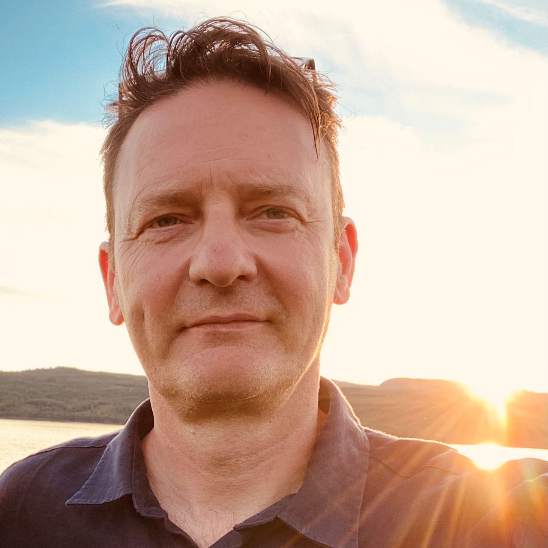 A picture of Peter Scott, a man with dark hair, at sunset on a beach.