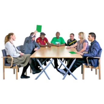 A group sitting around a table. One person holds up a green paper showing he's voting for something.