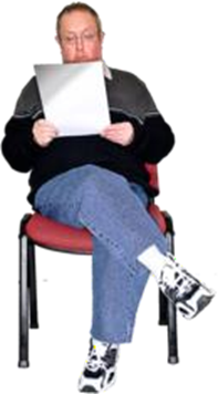 Person sitting crosslegged on a chair. They read a white document.