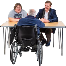 Man in wheelchair talking to two people behind a desk