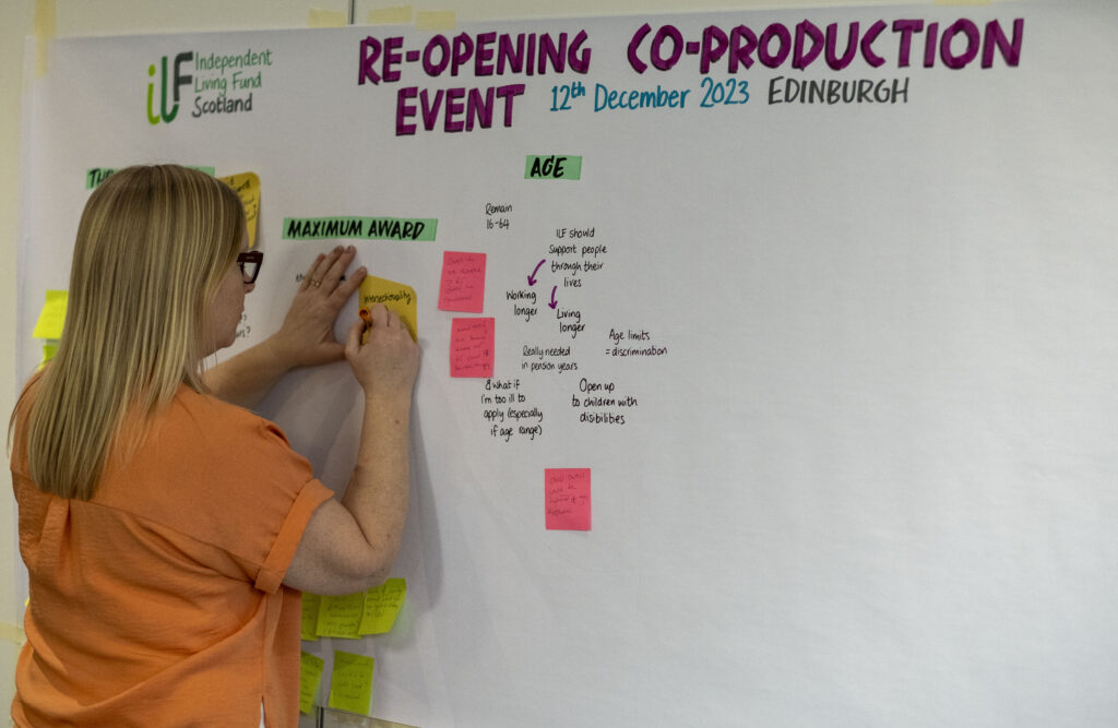 A graphic illustrator draws on a board with post-its on it.