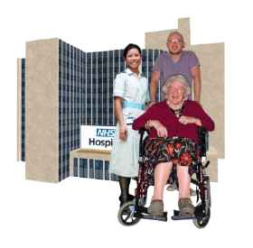A nurse stands beside an older lady in a wheelchair being pushed by a younger man. They all stand in front of a building with a sign half seen showing it's an NHS hospital.