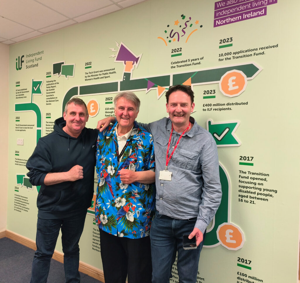 Three men stand in front of a timeline wall. Harvey Tilley, Jack Blaik OBE and Peter Scott OBE.