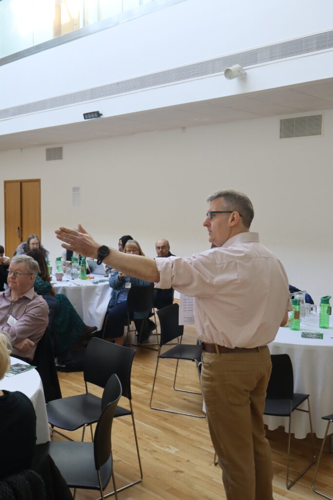 Our CFO, Harvey, talks to people sitting at tables. His arm is out to the side.