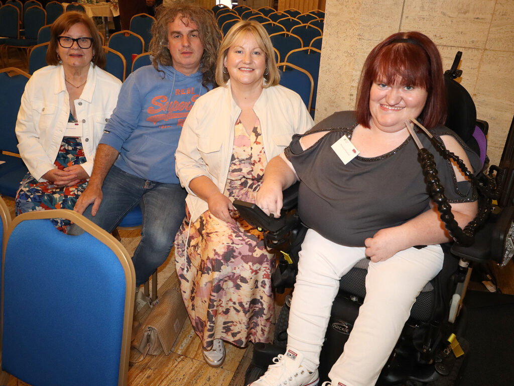 A group of people - 3 women, 1 man - pose in a row of seats.