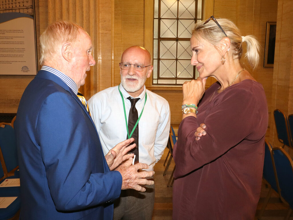 Two men talking to a lady who smiles at them.