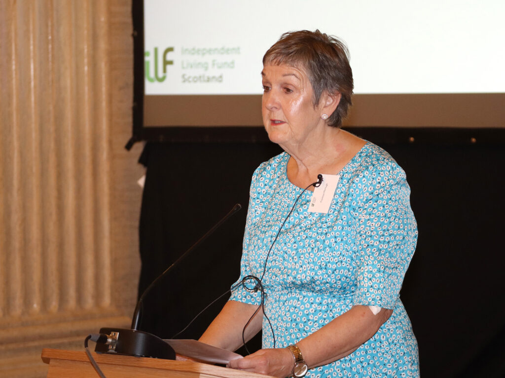 A lady in a blue dress stands at the podium.