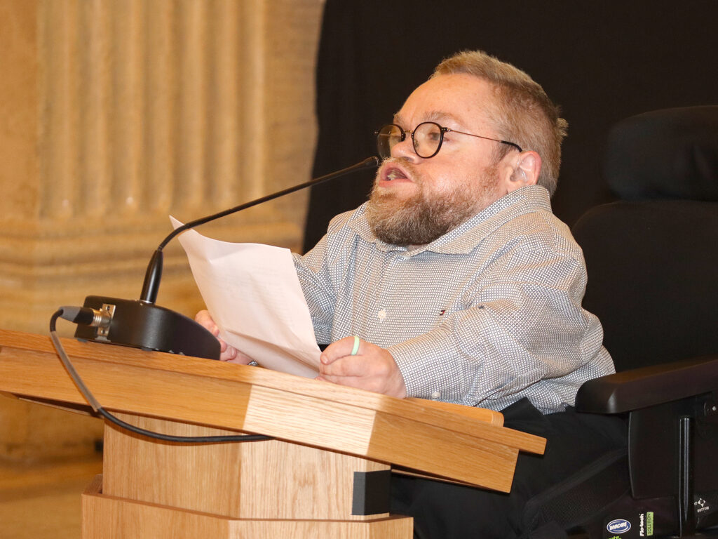 A young man is at the podium holding his speech.