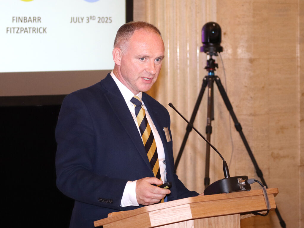 A man in a suit and tie stands at the podium.