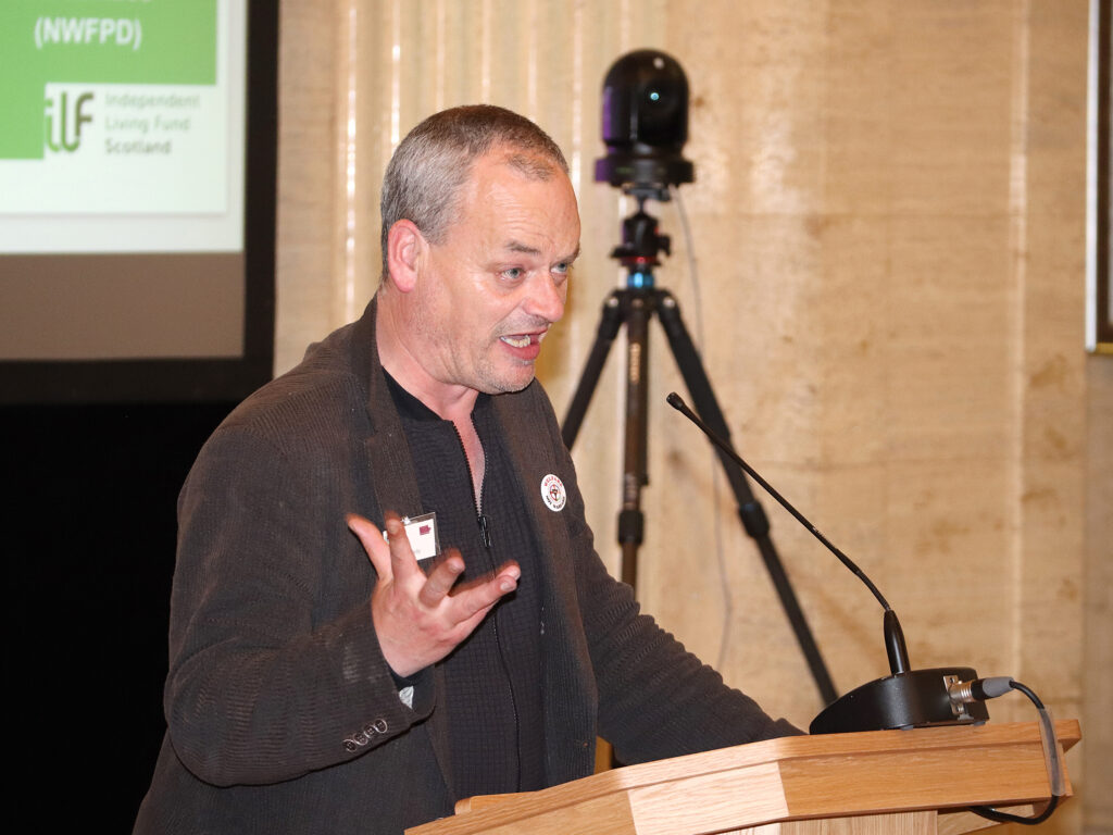 A man gestures as he stands at the podium.