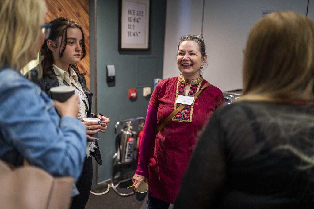 A lady in red laughs while talking to a group of three ladies.