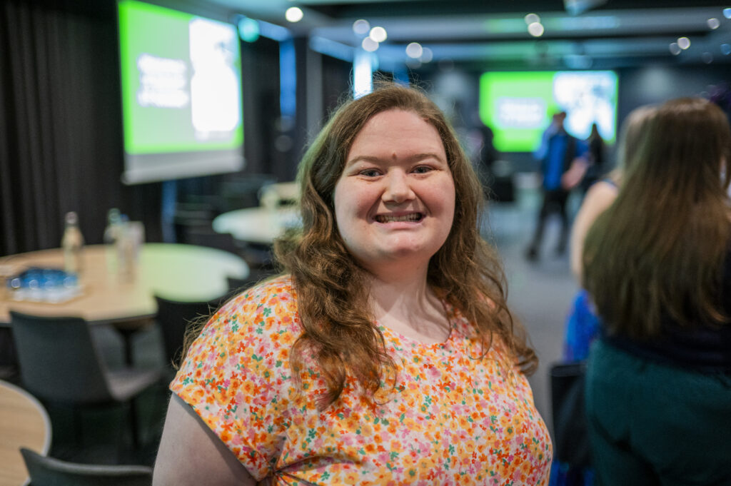 A lovely young lady in an orange spotty top, smiling at the camera.