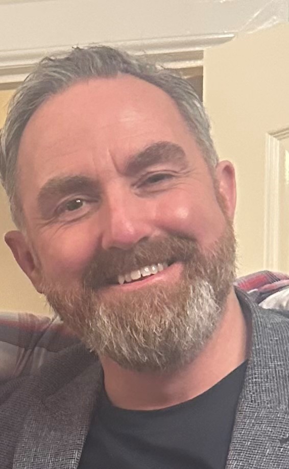 A photo of a man with a beard and a smile.