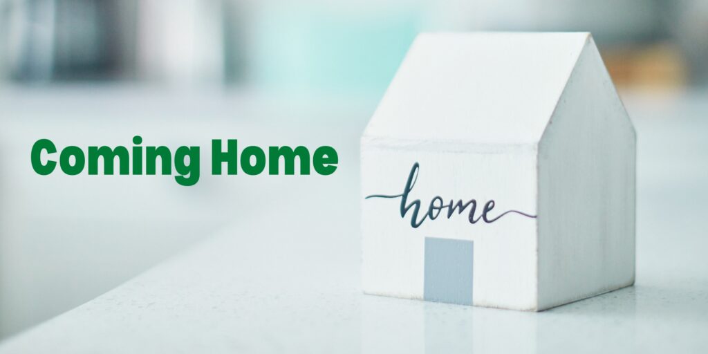 A small wooden house with home written on it sits in the foreground. In green text it reads: Coming