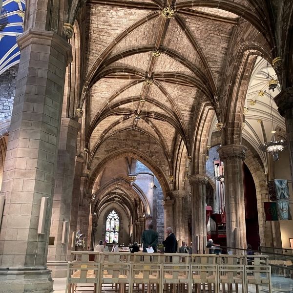 Interior of St Giles' Cathedral, showing high stone pillars, a vaulted ceiling, and grand arched beams.
