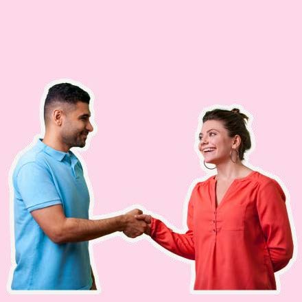 A man in blue shakes hands with a smiling woman in red.