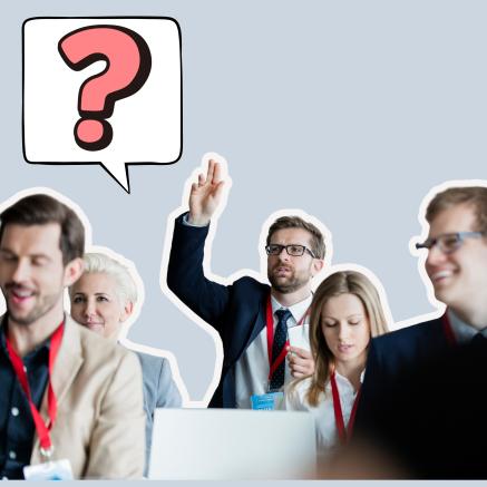 A man has his hand up to ask a question at a meeting. A speech bubble shows a big red question mark.