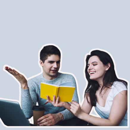 A woman laughs as she looks at a yellow book. A man holds up his hand as if asking a question.