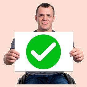 Man is holding a sign with a big green tick on it.