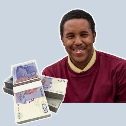 Man in maroon jumper with pile of cash in front of him.