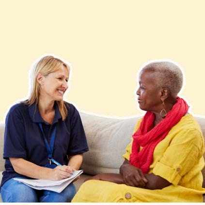 Two women chatting on a couch. One wears all blue. The other wears all yellow with a red scarf.