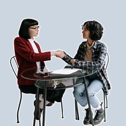 Two women shaking hands at a table.